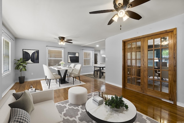 living area featuring a ceiling fan, healthy amount of natural light, wood finished floors, and baseboards
