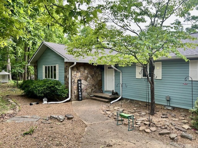 view of front of house featuring roof with shingles and stone siding
