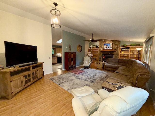 living room with ceiling fan, light wood finished floors, lofted ceiling, and a fireplace