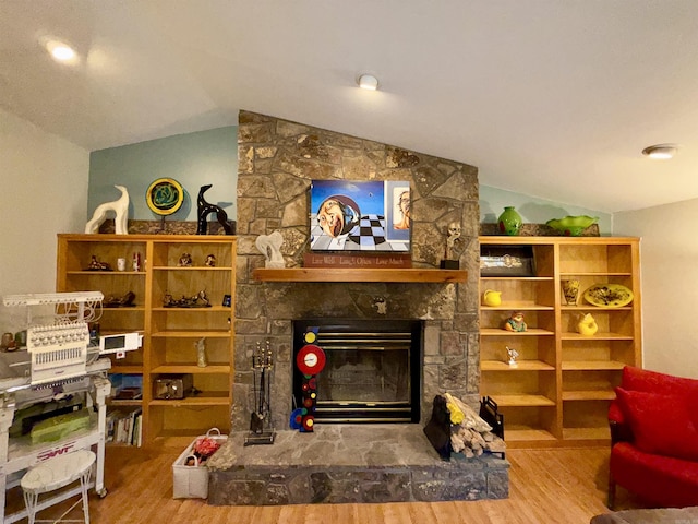 living area with wood finished floors, lofted ceiling, and a fireplace