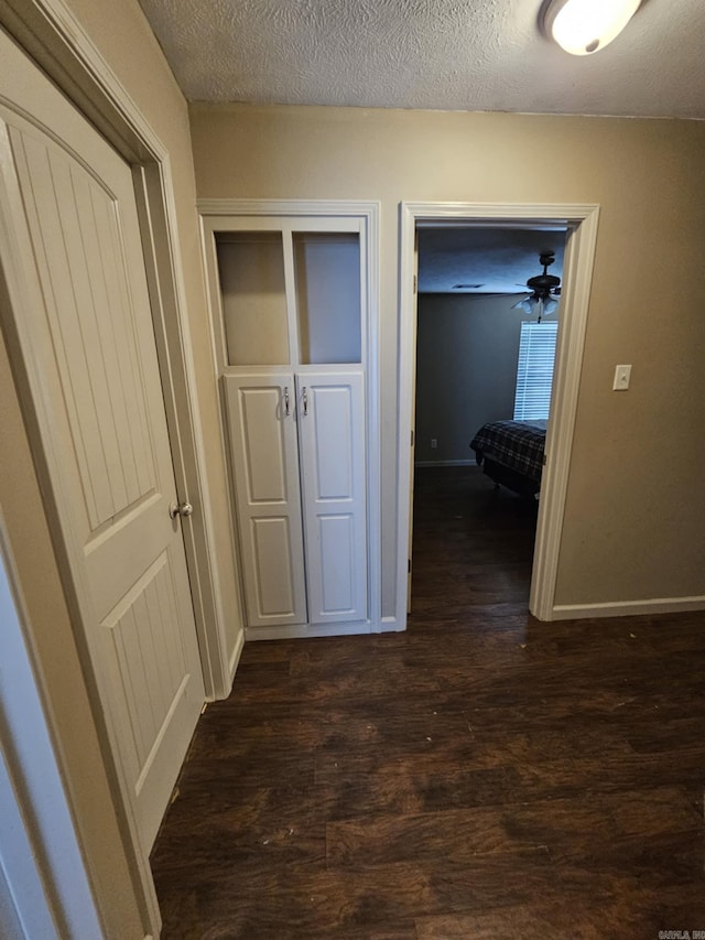 216 Plum Dr, Austin, AR 72023 - corridor featuring dark wood finished floors, baseboards, and a textured ceiling