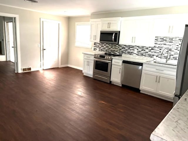 301 Coil, Steele, MO 63877 - kitchen with appliances with stainless steel finishes, a sink, backsplash, white cabinetry, and dark wood-type flooring