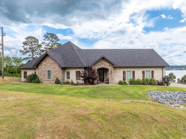 view of front of house with stone siding, a shingled roof, and a front yard