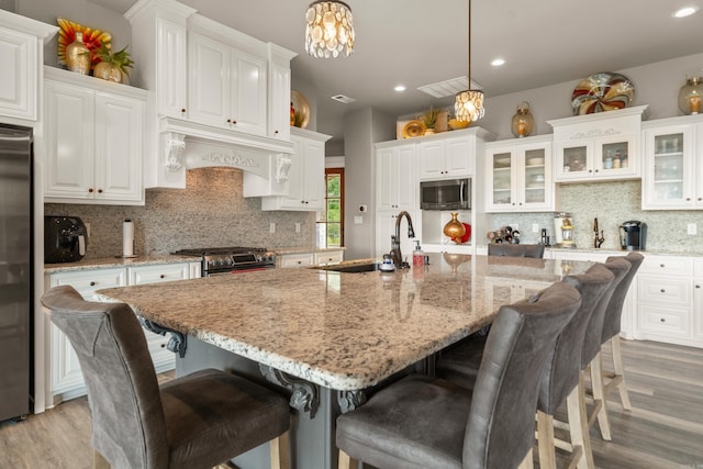 kitchen with stainless steel appliances, light wood-type flooring, white cabinets, recessed lighting, and decorative backsplash