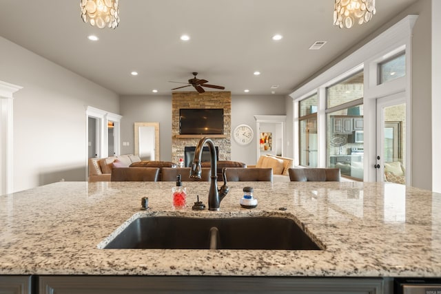 kitchen with open floor plan, a sink, recessed lighting, a ceiling fan, and a fireplace