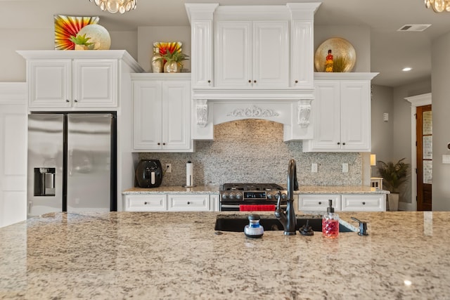kitchen featuring stainless steel appliances, light stone counters, white cabinetry, a chandelier, and recessed lighting