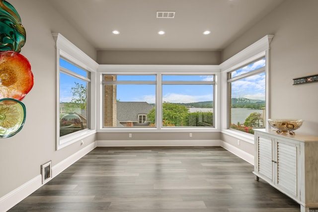 unfurnished sunroom with healthy amount of natural light, wood finished floors, recessed lighting, and baseboards