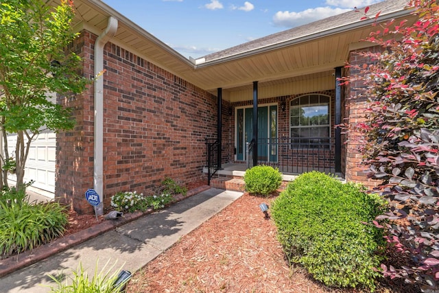 1045 Spatz Cir, Conway, AR 72034 - view of exterior entry featuring brick siding, an attached garage, and covered porch