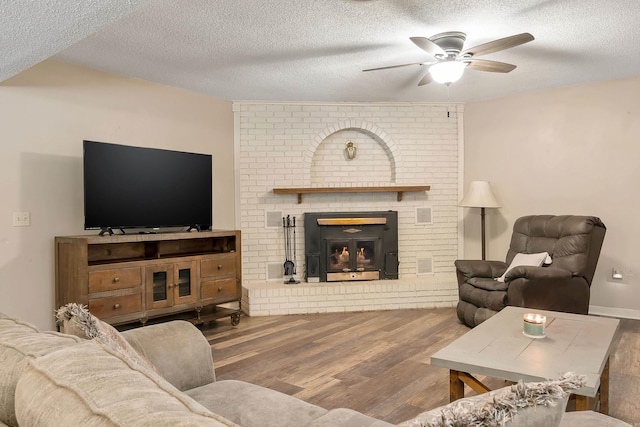 234 Robin Ln, Walnut Ridge, AR 72476 - living area featuring a ceiling fan, a textured ceiling, wood finished floors, and a brick fireplace