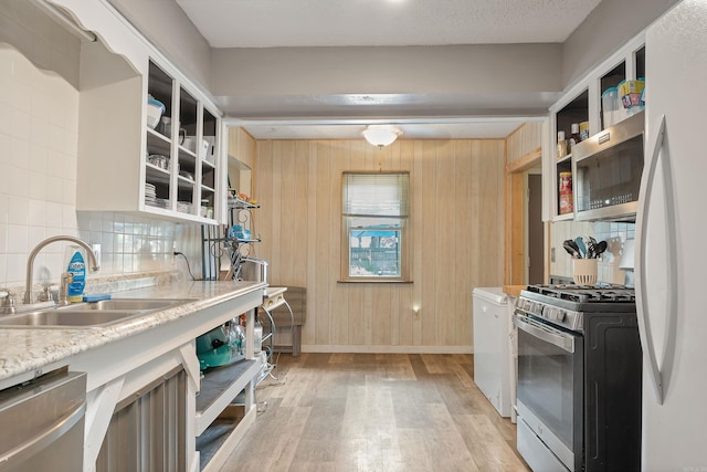 234 Robin Ln, Walnut Ridge, AR 72476 - kitchen featuring a sink, appliances with stainless steel finishes, open shelves, light wood finished floors, and wood walls