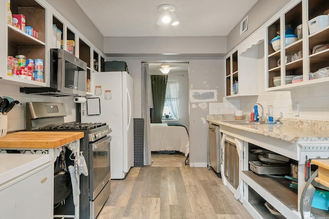 234 Robin Ln, Walnut Ridge, AR 72476 - kitchen with appliances with stainless steel finishes, open shelves, light wood-style flooring, backsplash, and a sink