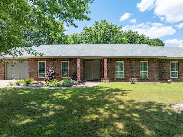 ranch-style home featuring a garage, brick siding, and a front yard