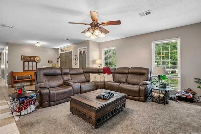 living area with ceiling fan, healthy amount of natural light, and a textured ceiling