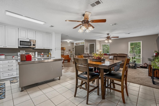 dining space featuring a ceiling fan, a textured ceiling, and light tile patterned floors