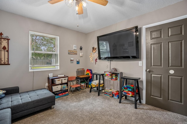 playroom with carpet, ceiling fan, and a textured ceiling
