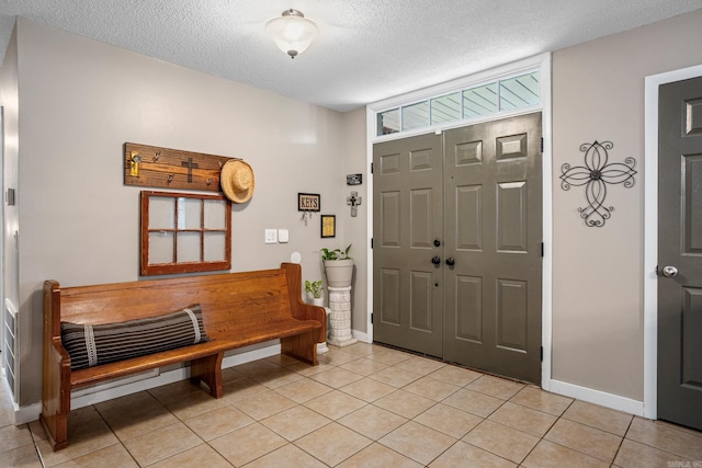 entrance foyer featuring baseboards, light tile patterned flooring, and a textured ceiling