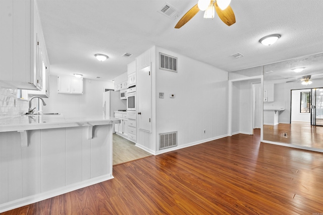 6500 W 12th St, Little Rock, AR 72204 - unfurnished living room with ceiling fan, a sink, wood finished floors, baseboards, and a textured ceiling