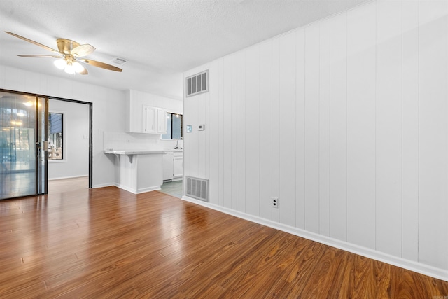 6500 W 12th St, Little Rock, AR 72204 - unfurnished living room featuring wood finished floors, a ceiling fan, baseboards, and a textured ceiling