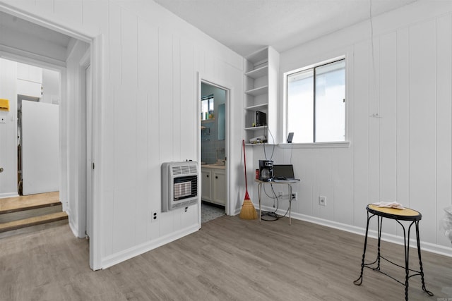 6500 W 12th St, Little Rock, AR 72204 - interior space featuring heating unit, wood finished floors, a decorative wall, and baseboards