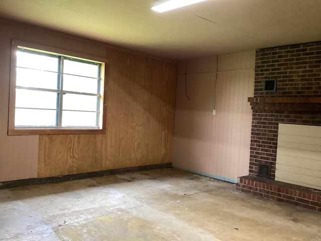 228 Nevada 66 W, Prescott, AR 71857 - empty room featuring wooden walls, unfinished concrete floors, and a fireplace