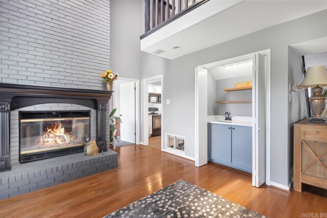 38 Ninth Fairway Loop, Maumelle, AR 72113 - living room featuring wood finished floors, a brick fireplace, baseboards, and a towering ceiling