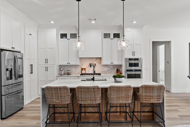 2505 Collins Dr, Conway, AR 72058 - kitchen with stainless steel appliances, light wood-style flooring, white cabinetry, glass insert cabinets, and backsplash