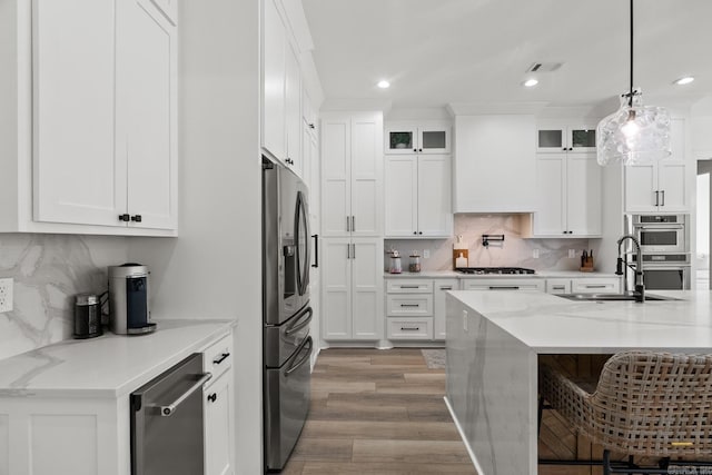 2505 Collins Dr, Conway, AR 72058 - kitchen with stainless steel appliances, a sink, light wood-type flooring, backsplash, and white cabinets