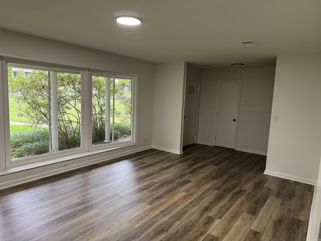 empty room featuring baseboards and dark wood finished floors