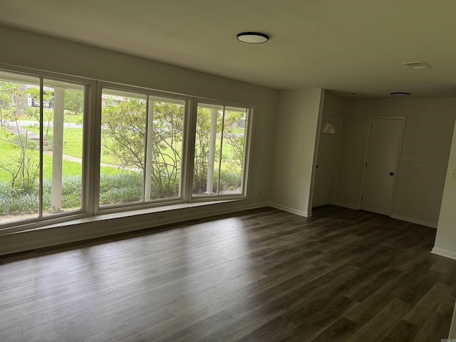 spare room with baseboards and dark wood-style flooring