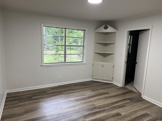 unfurnished bedroom with ornamental molding, dark wood finished floors, multiple windows, and baseboards