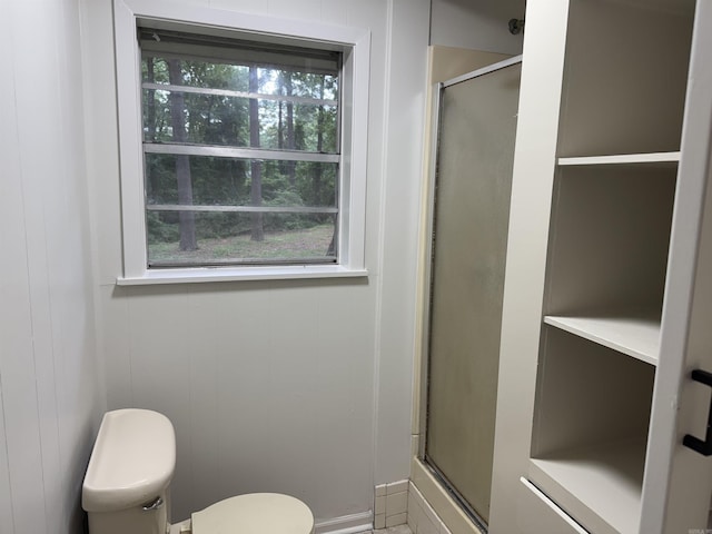 bathroom featuring a shower with shower door, healthy amount of natural light, and toilet