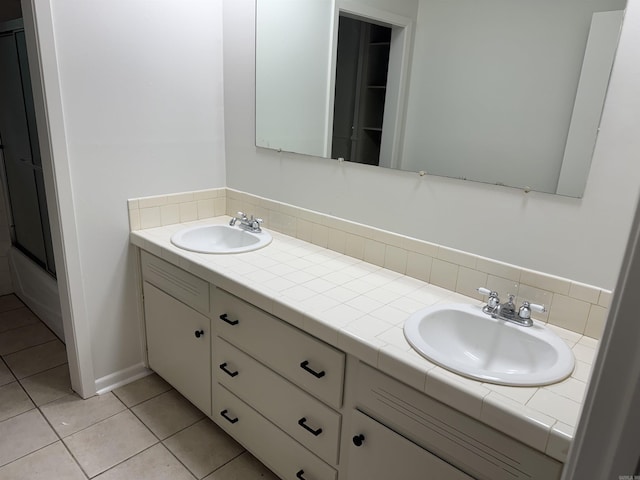 full bathroom with double vanity, tile patterned flooring, a shower with door, and backsplash