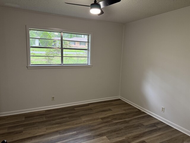 spare room featuring dark wood finished floors, a ceiling fan, a textured ceiling, baseboards, and ornamental molding