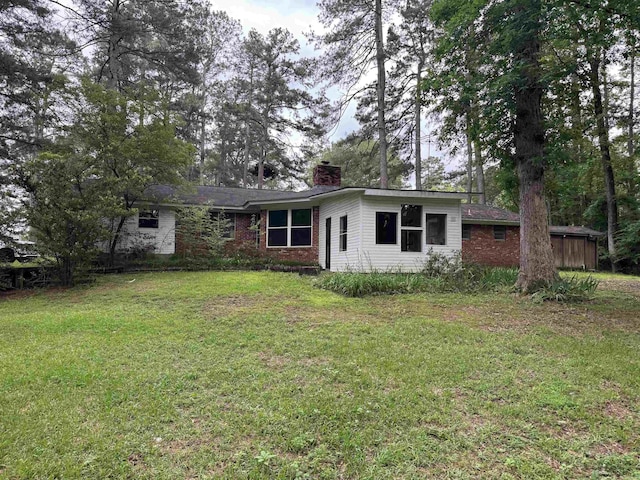 view of front of house featuring a chimney, a front lawn, and brick siding