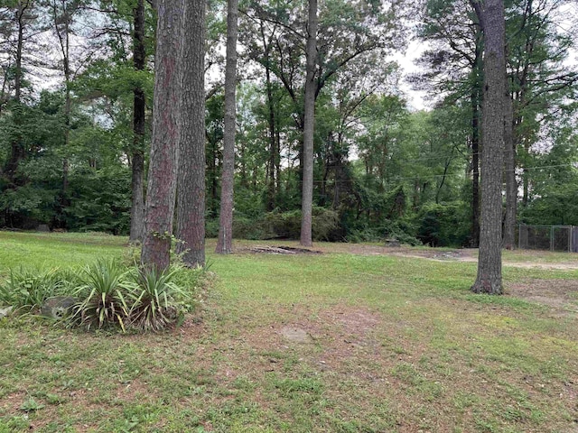 view of grassy yard featuring a forest view