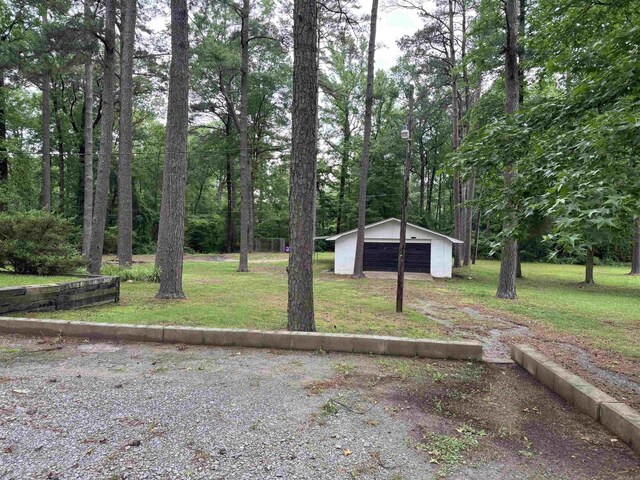 view of green lawn with a garage and an outbuilding