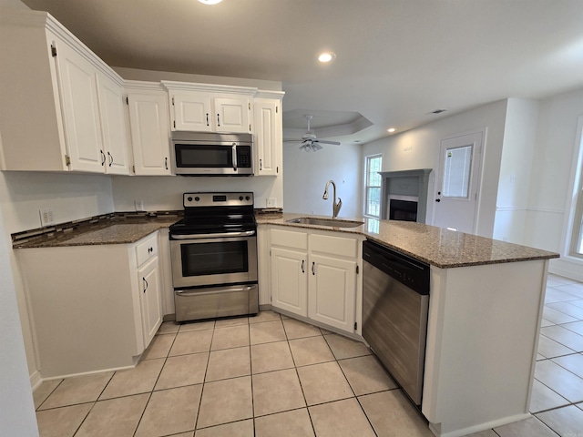 19 Twin Lks, Cabot, AR 72023 - kitchen with stainless steel appliances, a sink, a peninsula, light tile patterned flooring, and a fireplace