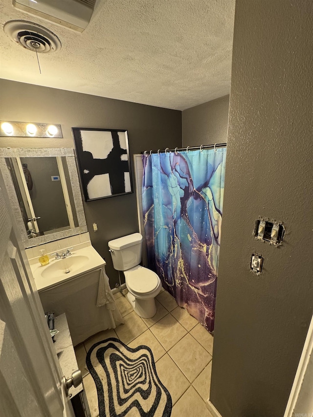 bathroom featuring toilet, tile patterned flooring, vanity, a textured ceiling, and a textured wall
