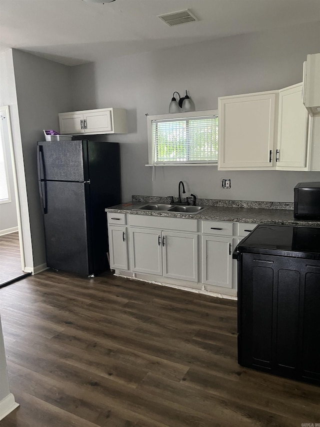 kitchen featuring a sink, freestanding refrigerator, and white cabinetry