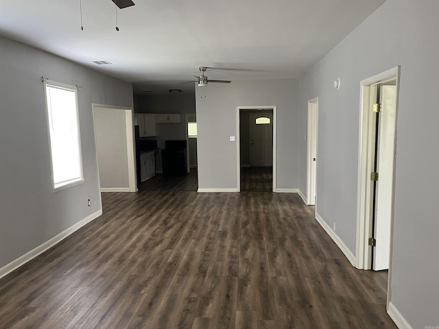 unfurnished living room with ceiling fan, dark wood-style flooring, and baseboards