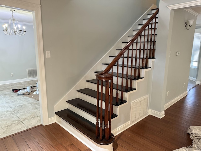 stairway with wood-type flooring, ornamental molding, baseboards, and a chandelier