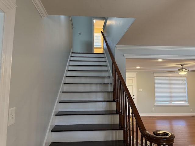 staircase featuring wood finished floors, a ceiling fan, baseboards, ornamental molding, and recessed lighting