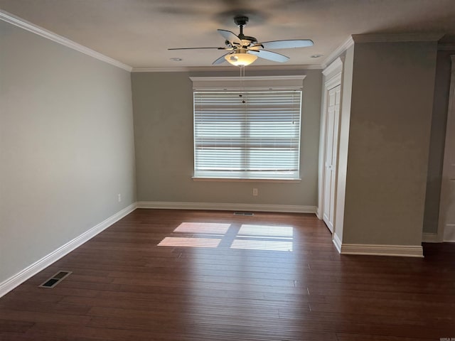 empty room with crown molding, a ceiling fan, dark wood-type flooring, and baseboards