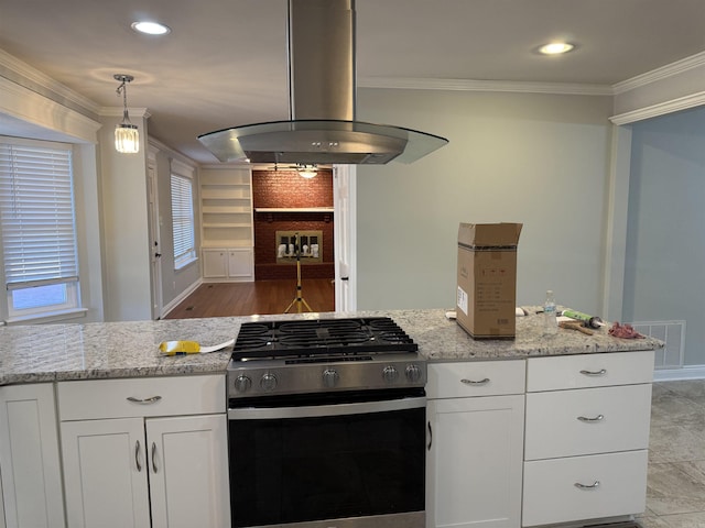 kitchen with gas stove, island exhaust hood, white cabinets, ornamental molding, and light stone counters