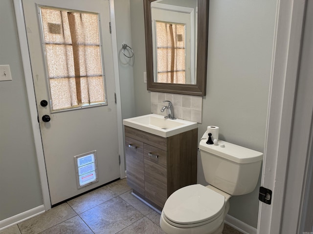 bathroom with vanity, tasteful backsplash, toilet, tile patterned flooring, and baseboards