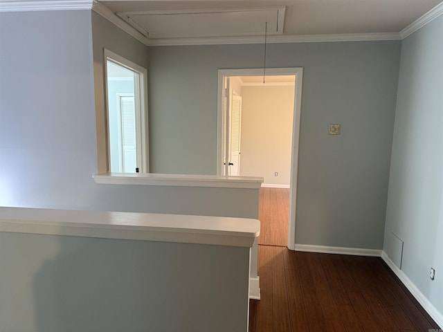 hallway featuring attic access, dark wood-style flooring, baseboards, and crown molding
