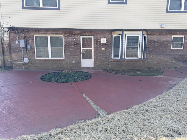view of exterior entry featuring a patio and brick siding