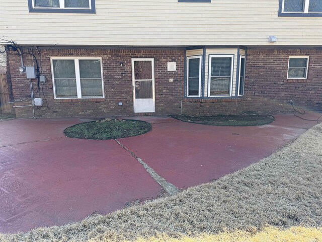 view of exterior entry with a patio and brick siding