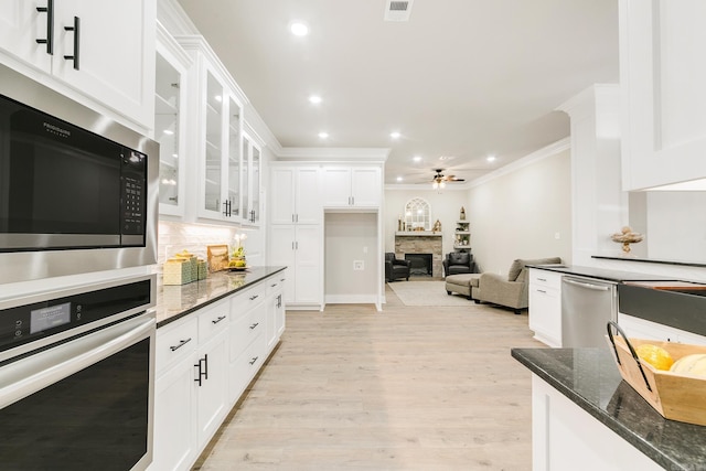 50 Wellington Pl, Cabot, AR 72023 - kitchen with appliances with stainless steel finishes, a fireplace, white cabinetry, decorative backsplash, and ceiling fan