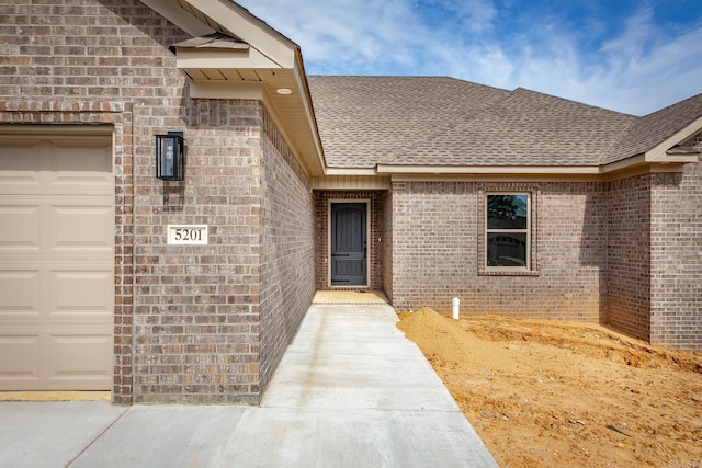 5201 Canter Ln, Jacksonville, AR 72076 - property entrance featuring an attached garage, a shingled roof, and brick siding